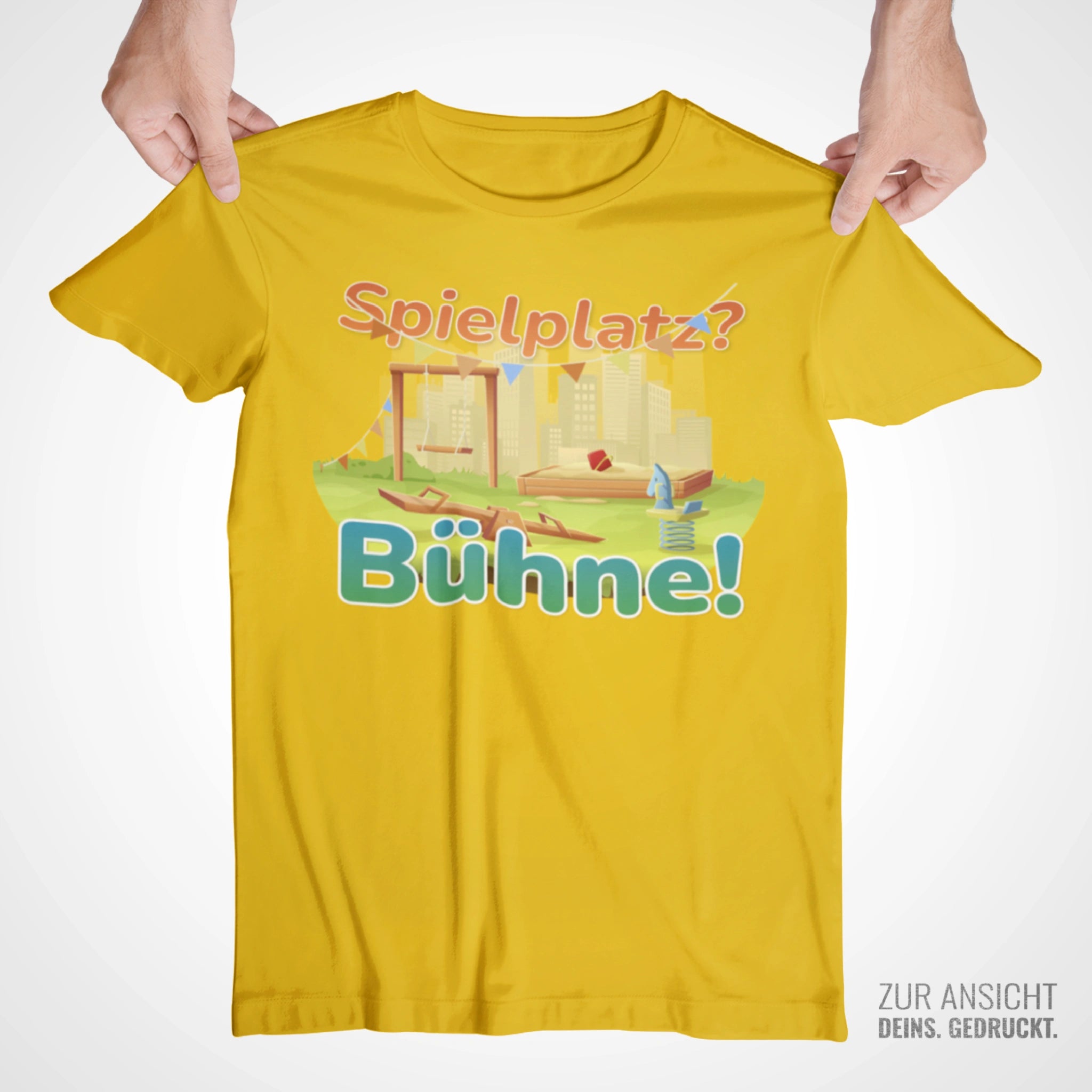 Gelbes Kindershirt mit Aufdruck „Spielplatz? Bühne!“ und bunter Illustration eines Spielplatzes, freigestellt auf hellem Hintergrund.