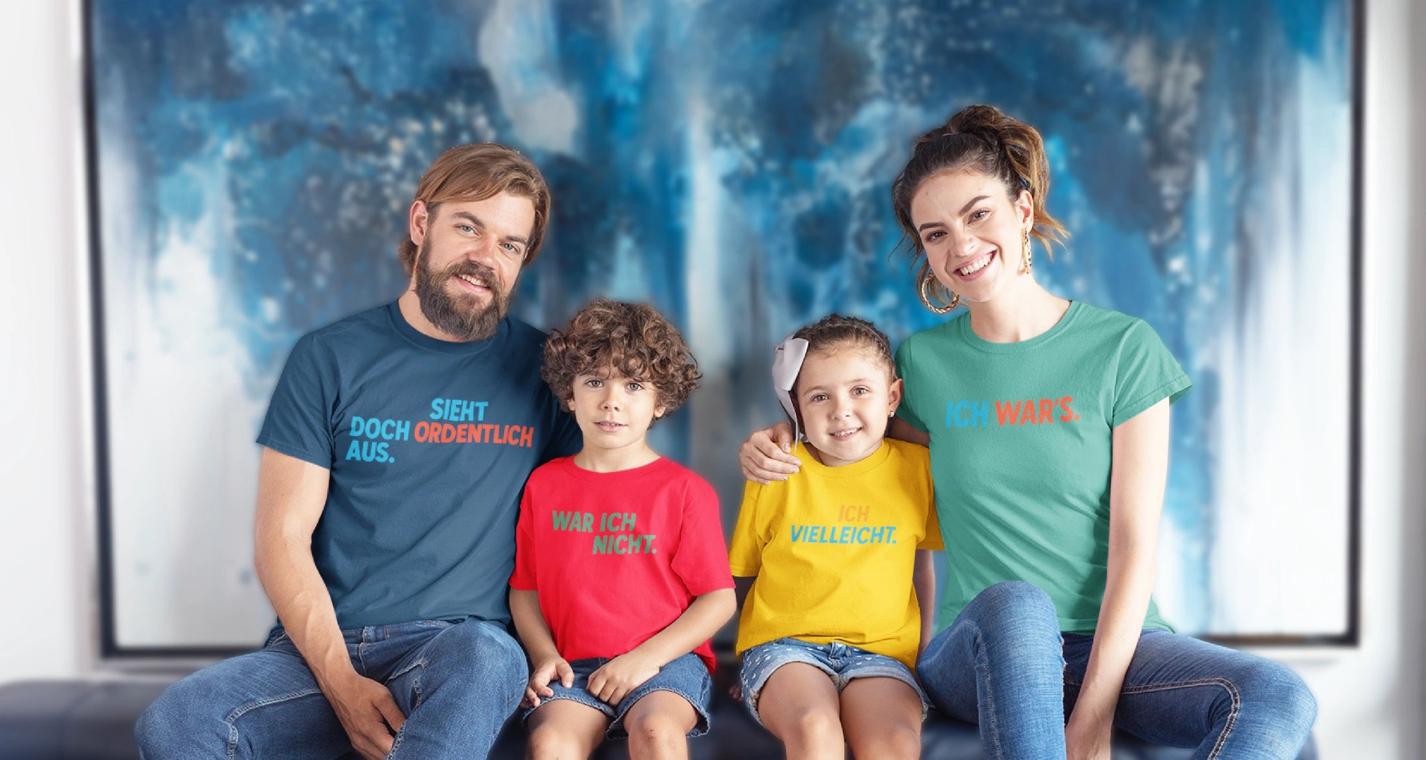 Vier Personen auf dem Sofa mit bunten T-Shirts. Aufdrucke: ‚Sieht doch ordentlich aus‘, ‚War ich nicht‘, ‚Ich vielleicht‘, ‚Ich war’s‘.