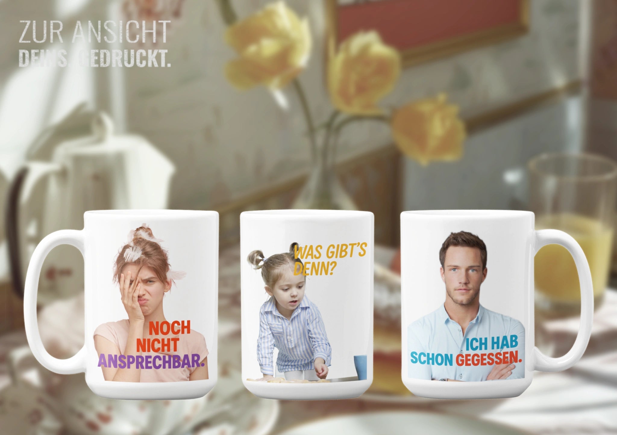 Drei Tassen nebeneinander mit Sprüchen: „Noch nicht ansprechbar“, „Was gibt’s denn?“, „Ich hab schon gegessen“ – vor Frühstückskulisse.